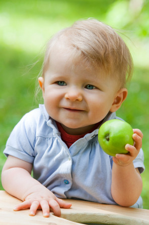 Outdoor Portrait eines Kindes im Grünen mit Apfel in Hand