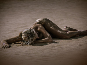 Bodypainting einer Frau, liegend am Strand in Braun