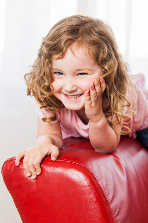 Kinder Fotoshooting, Mädchen auf rotem Sofa