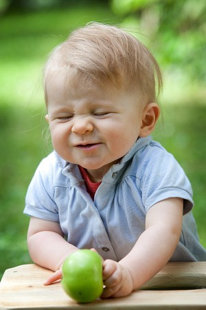 Kinder Fotoshooting, Portrait eines Kindes in Natur, das in einen sauen Apfel beißt